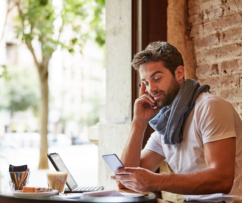 A person checking a phone beside a tablet.